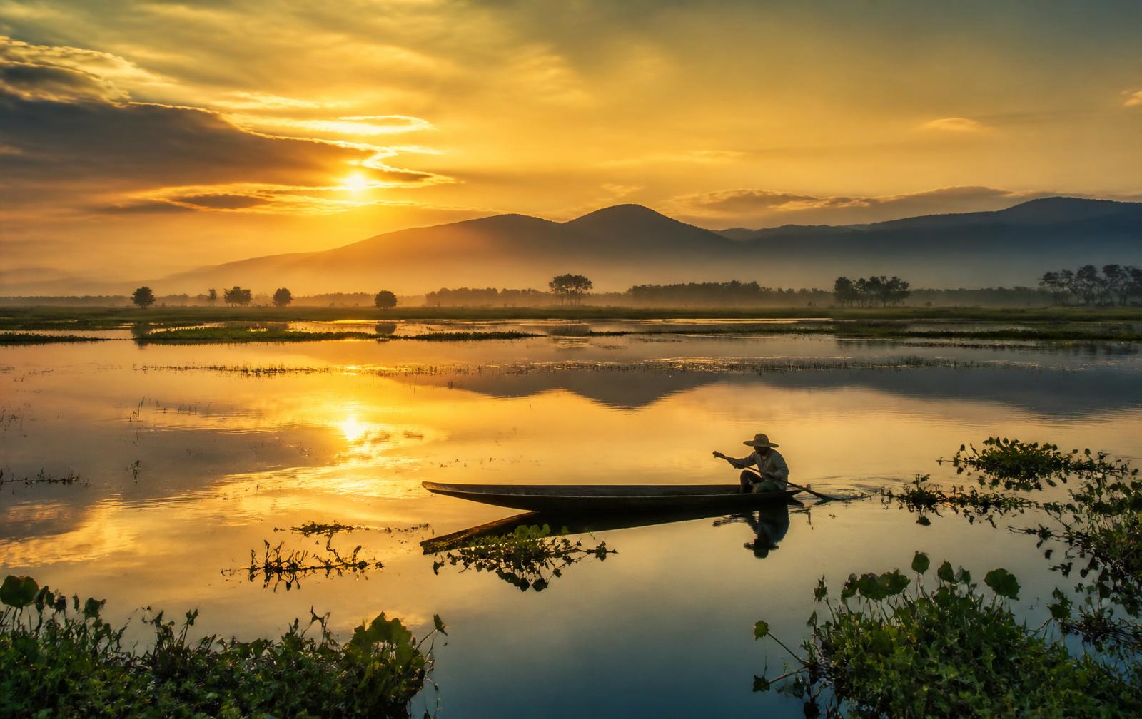 Sunrise over the haor wetlands of Sunamganj with a fisherman's boat
